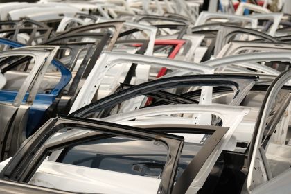 Portas de carros de diferentes cores dispostas em um desmanche de veículos.