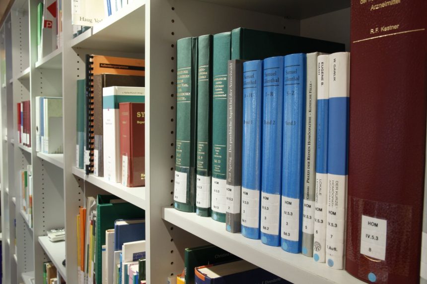 Estantes organizadas com livros em uma biblioteca contemporânea, representando acervo, preservação e acesso ao conhecimento.